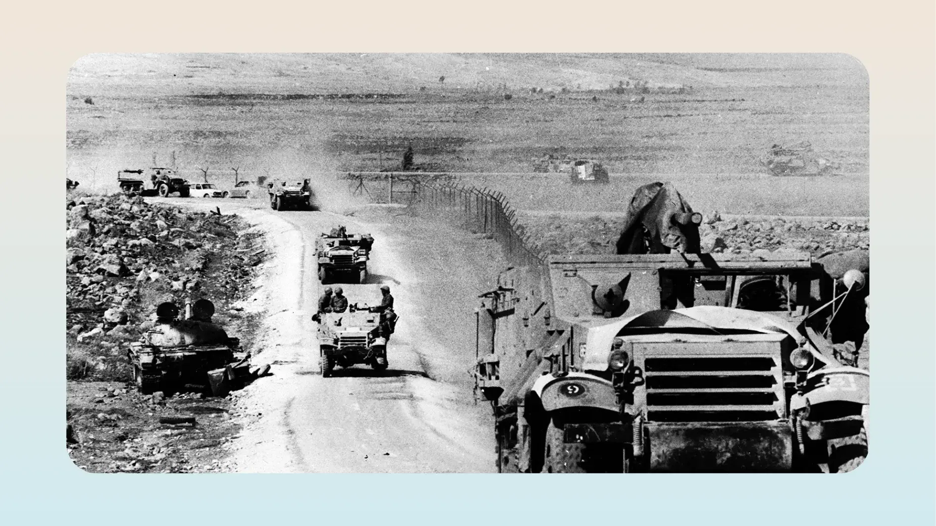 Black-and-white photograph of a military convoy traveling through a desert landscape